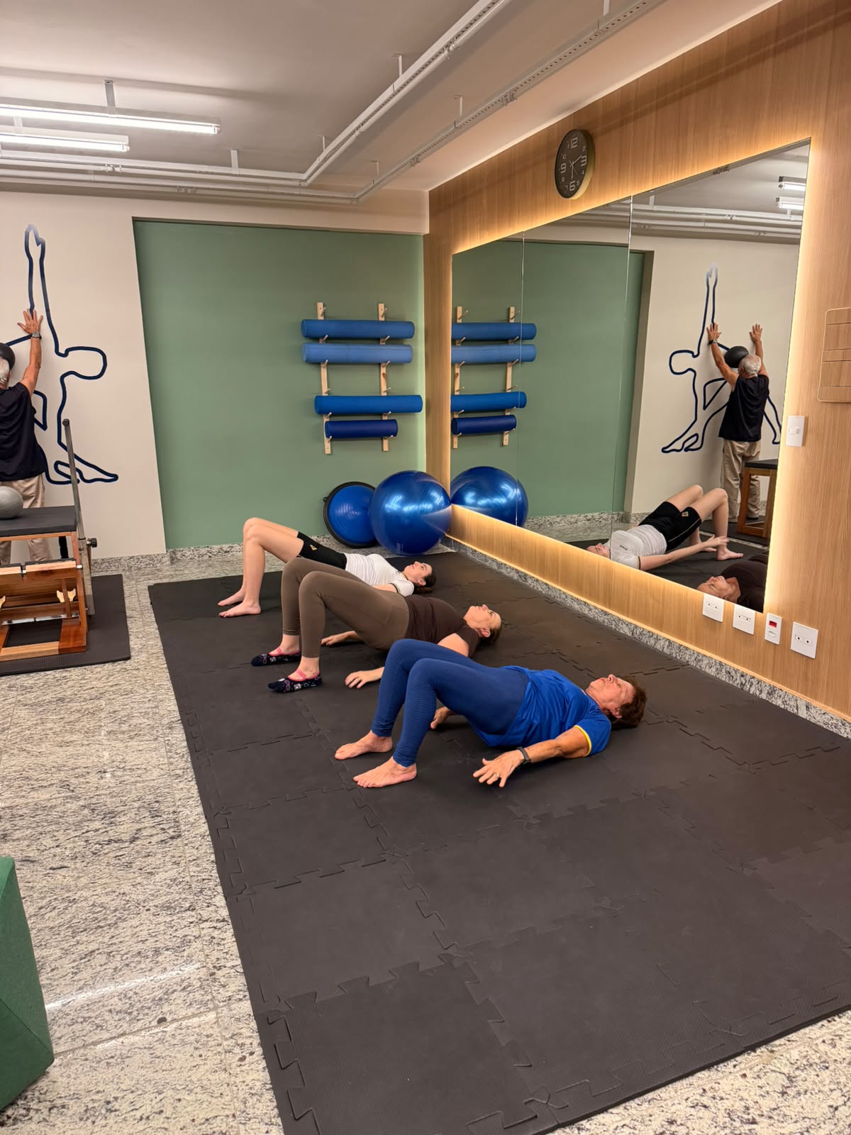 Pessoas praticando exercícios de Pilates no estúdio.